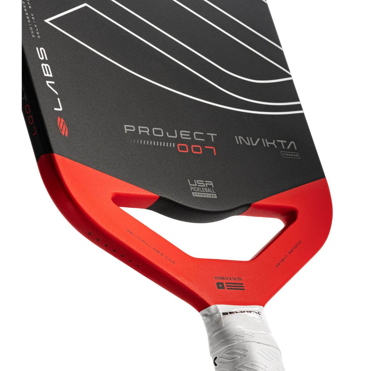 Close-up van de Selkirk LABS 007 Invikta pickleball paddle, zwart blad met rode onderzijde, wit handvat en het Selkirk-logo in zwart met witte omlijning op het slagooppervlak.