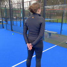 Padel speelster op veld met zwarte leggings en zwart vestje van Pace